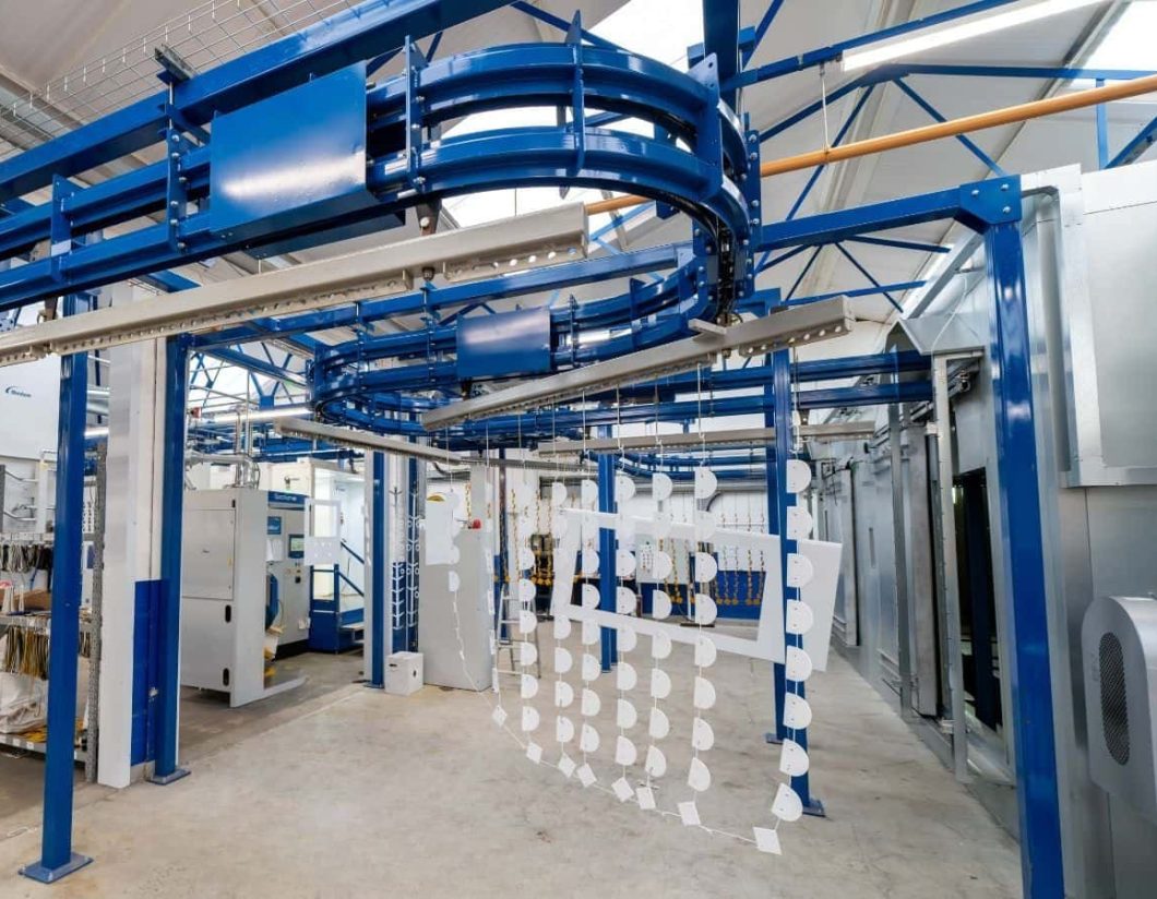 Powder coating line with overhead conveyor and hanging metal parts in Midlands facility
