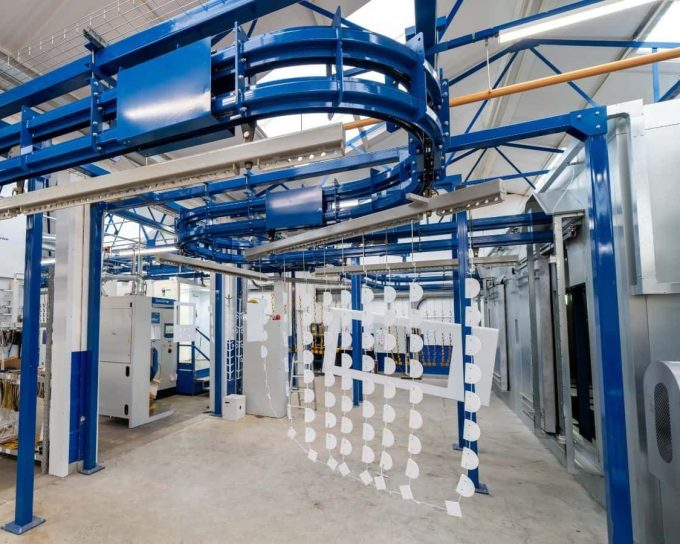 Powder coating line with overhead conveyor and hanging metal parts in Midlands facility