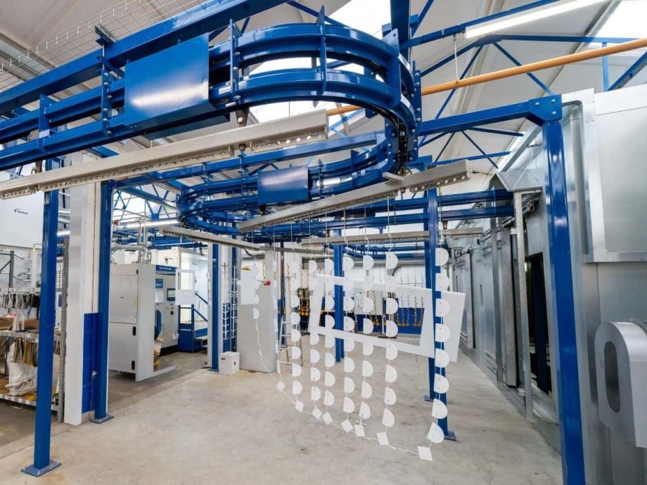 Powder coating line with overhead conveyor and hanging metal parts in Midlands facility
