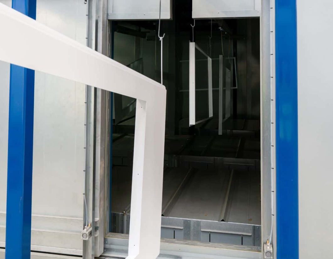 Metal components on conveyor entering powder coating process