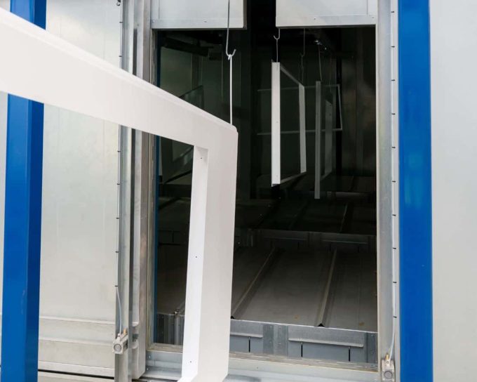 Metal components on conveyor entering powder coating process