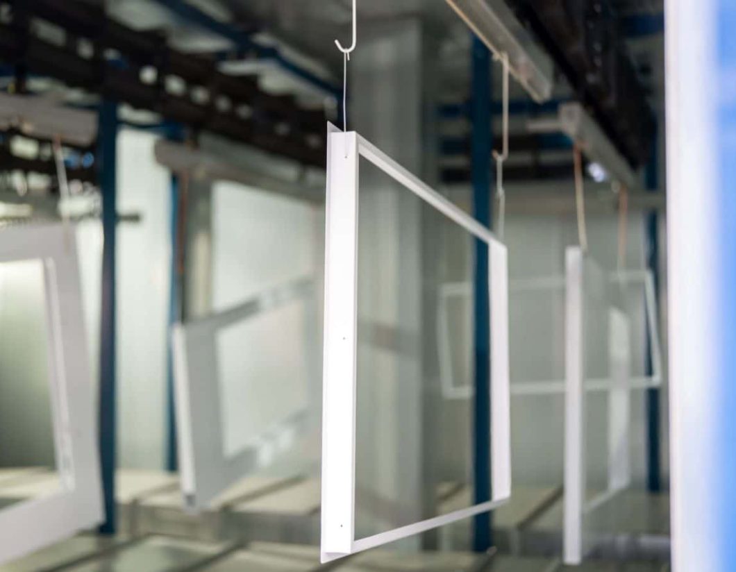 Sheet metal frames hanging on conveyor in powder coating line UK