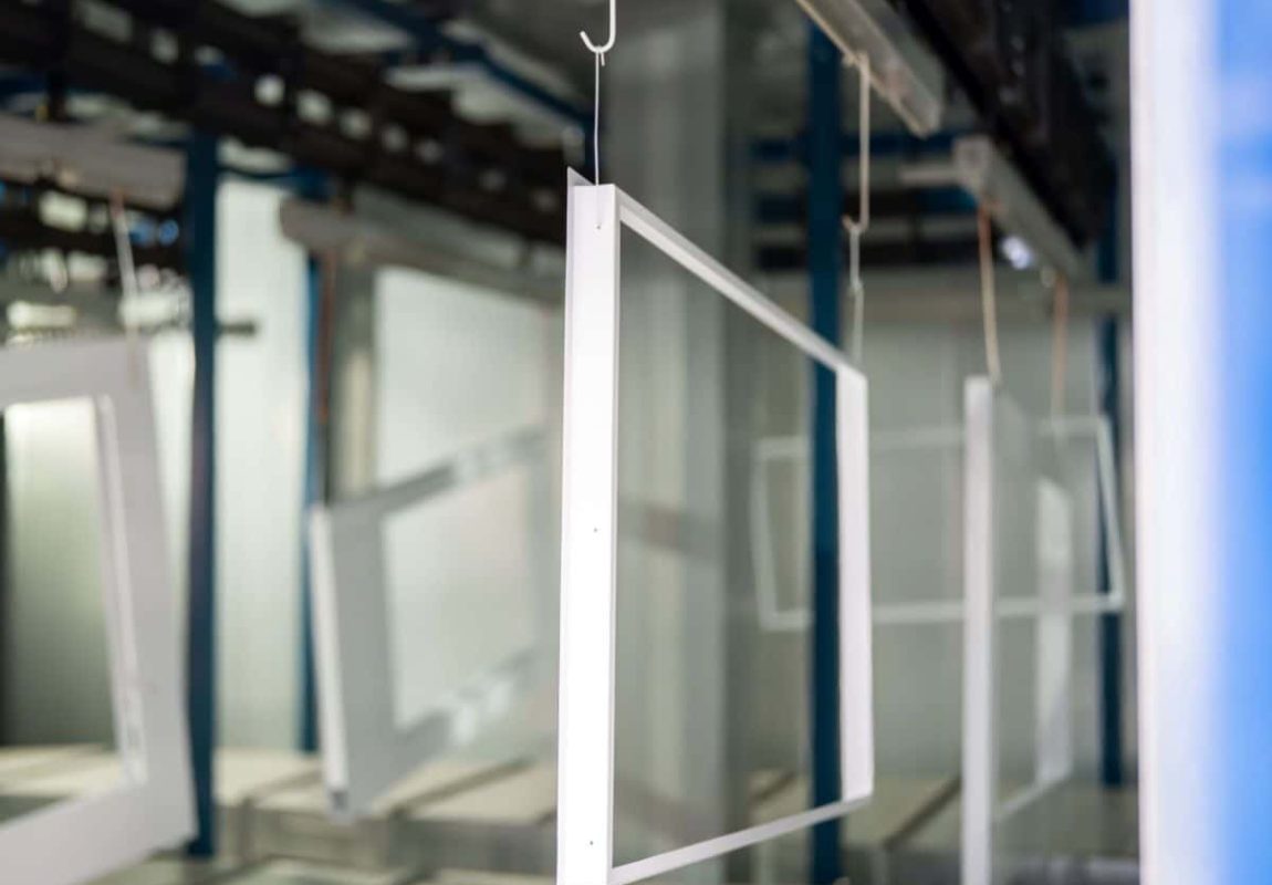 Sheet metal frames hanging on conveyor in powder coating line UK