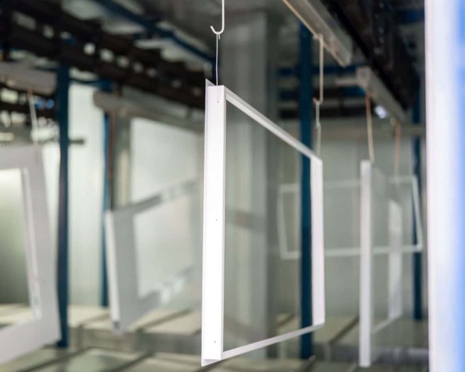 Sheet metal frames hanging on conveyor in powder coating line UK